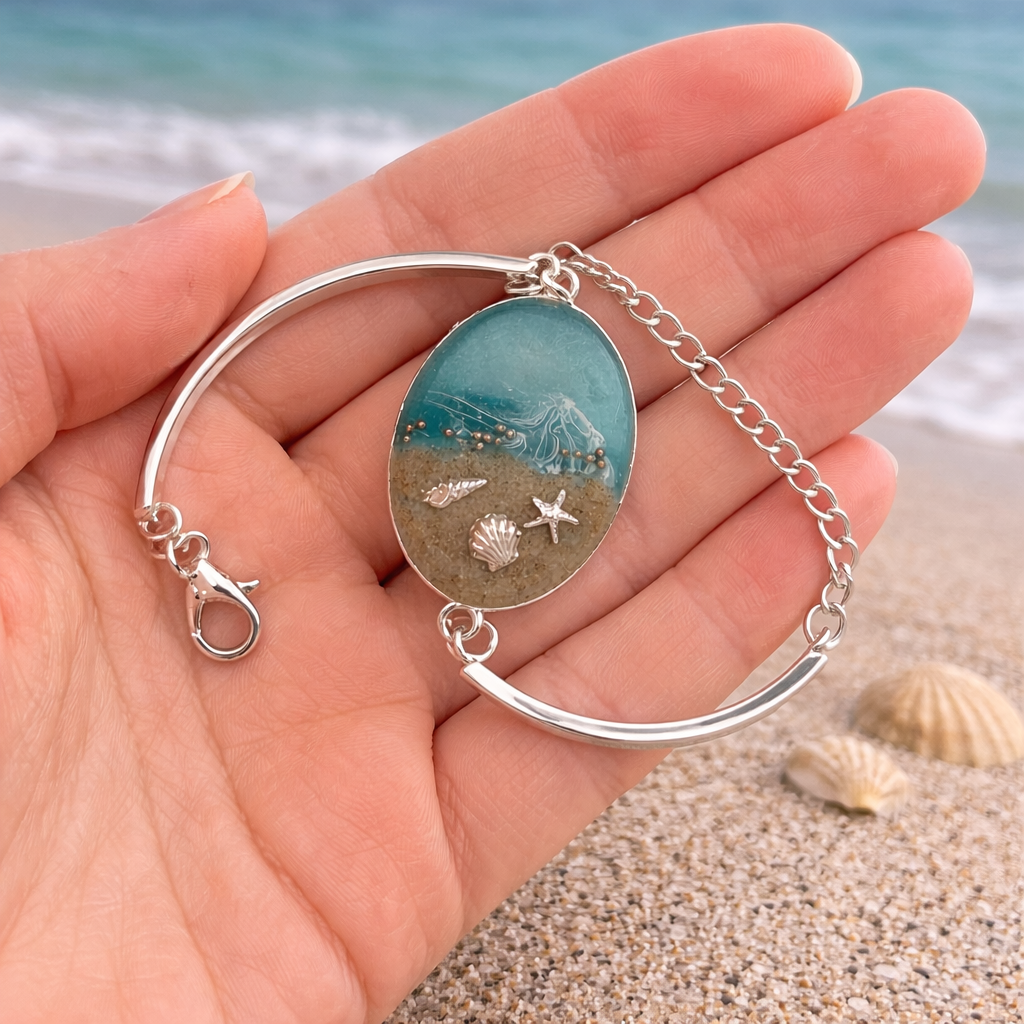 Isle of Wight resin bracelet with real beach sand, shells and starfish on adjustable silver bangle in hand for scale