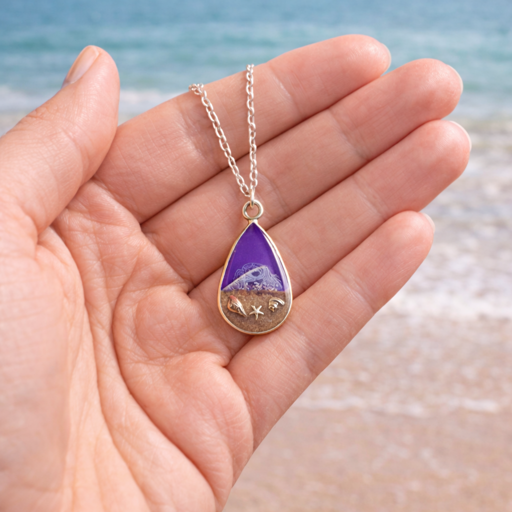 Purple resin teardrop necklace with Isle of Wight sand and shell charms on silver chain show in hand to scale