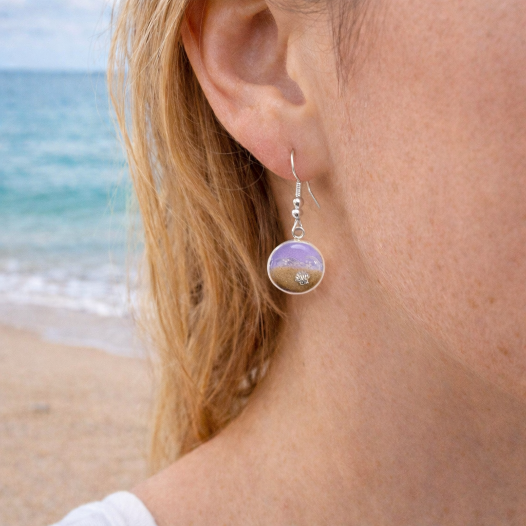 A Woman wearing Purple resin beach earrings with sand and shell charm on silver hooks