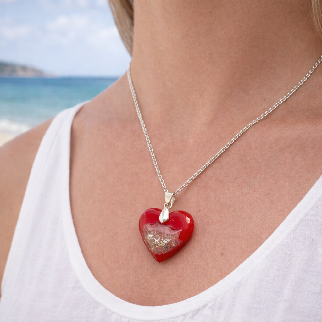 Woman wearing handmade turquoise resin heart necklace containing real Isle of Wight beach sand by the sea.