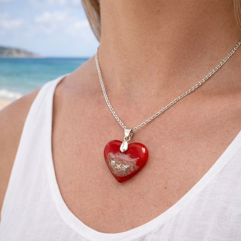 Woman wearing handmade turquoise resin heart necklace containing real Isle of Wight beach sand by the sea.