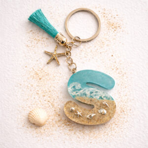 Isle of Wight letter S resin keyring with sand, wave design and starfish charm on neutral background