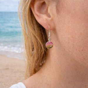 A Woman wearing pink resin beach earrings with sand and shell charm on silver hooks