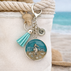 Isle of Wight resin keyring with real beach sand, seahorse charm, seahorse and turquoise tassel shown on beach bag
