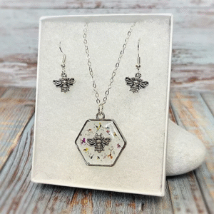Isle of Wight handmade bee necklace and matching earrings set displayed in a white gift box with silver details and dried flowers in resin