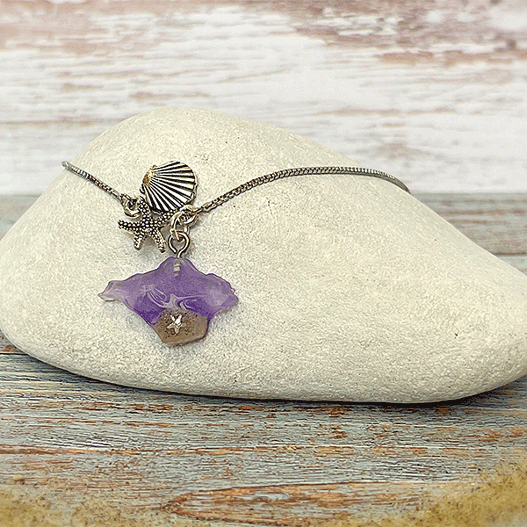 Isle of Wight purple resin shell and starfish bracelet with sand and silver charms on a linen background