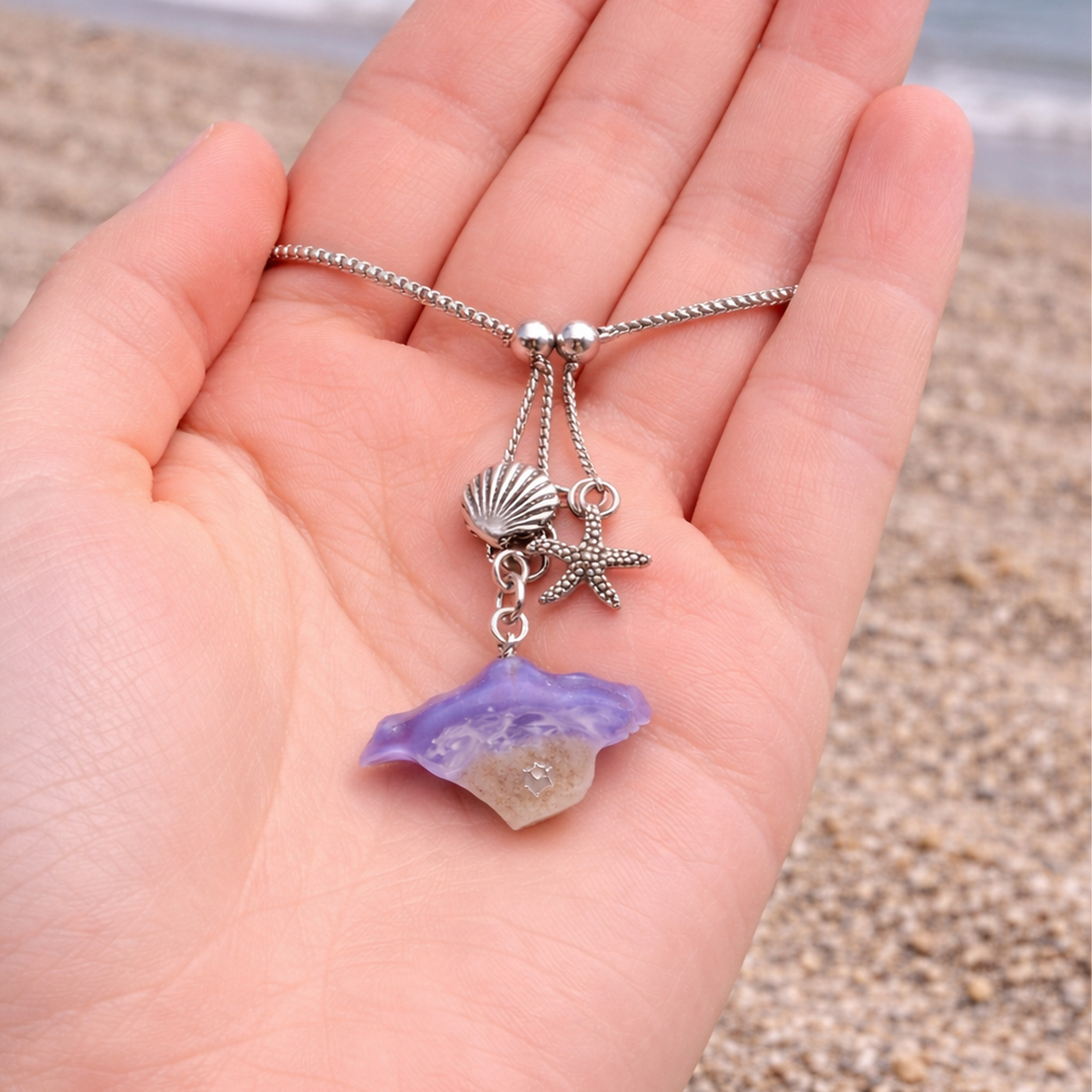 Purple resin shell and starfish bracelet held in hand showing size and detail of the handmade design