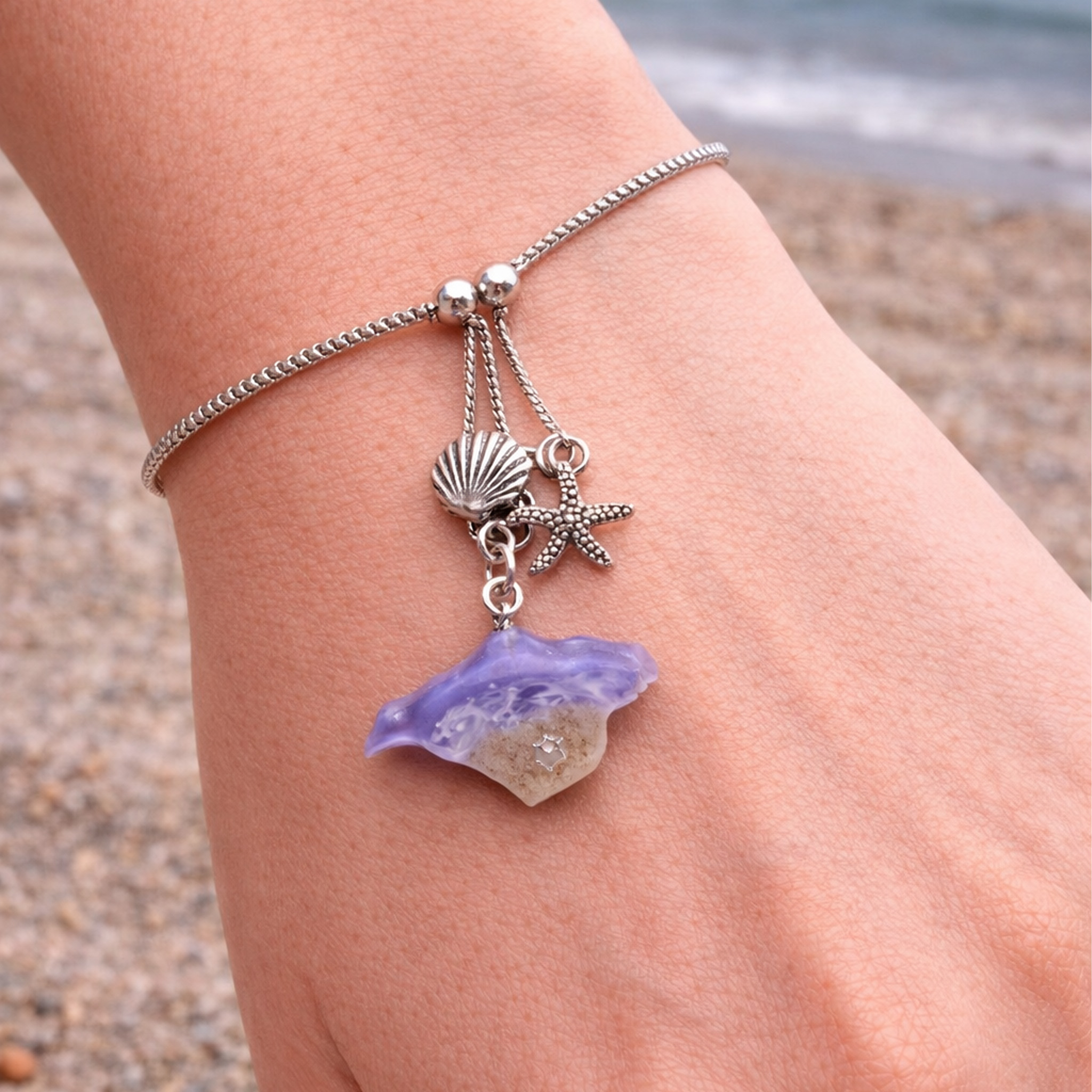 Purple resin shell and starfish charm bracelet worn on the beach showing adjustable fit and coastal style