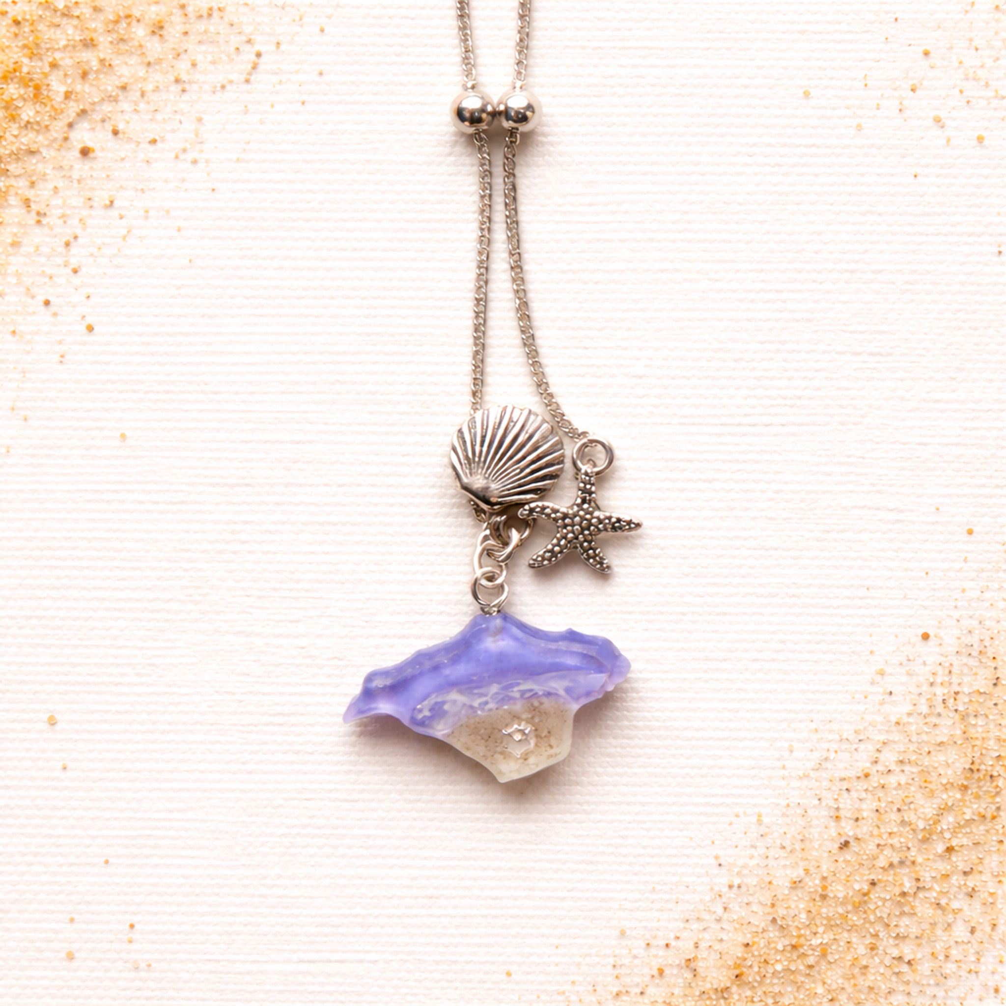 Isle of Wight purple resin shell and starfish bracelet with sand and silver charms on a linen background