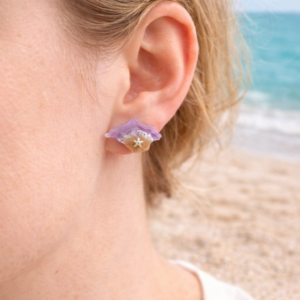 Isle of Wight resin earrings worn on ear with purple coastal design and beach background