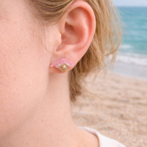 Isle of Wight resin earrings worn on ear with pink coastal design and beach background