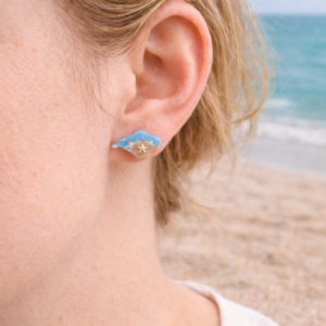 Isle of Wight resin earrings worn on ear with turquoise coastal design and beach background
